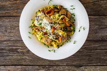 Tagliatelle with roast pork loin, parmesan cheese and mushrooms served on wooden table
