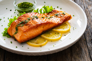 Seared salmon steak with lettuce and lemon on wooden table
