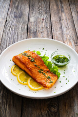 Seared salmon steak with lettuce and lemon on wooden table
