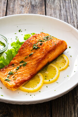 Seared salmon steak with lettuce and lemon on wooden table

