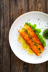 Seared salmon steak with lettuce and lemon on wooden table
