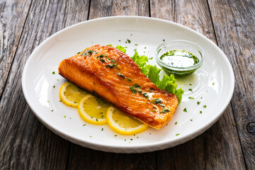 Seared salmon steak with lettuce and lemon on wooden table
