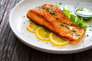 Seared salmon steak with lettuce and lemon on wooden table
