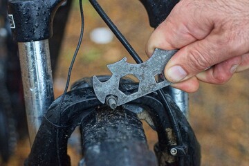 unscrewing an iron nut with an old mechanical adjustable hand iron pocket retro bicycle wrench of a...