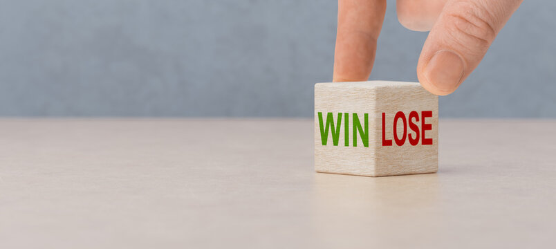 Win or lose, business concept. Businessman hand turns wooden cubes and changes word Lose to Win. Wooden cubes with win and lose text standing on table