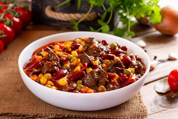 Goulash, beef stew or mexican dish chili con carne soup with meat, vegetables and spices on table.