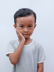 Portrait of a little asian boy holding his cheek with a toothache. suffering from toothache pain in mouth