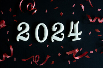 close up white color of number 2024 shape on black color background with red rolling ribbon and...