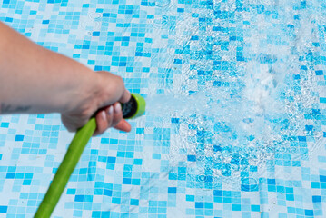 Garden pool. Water jet from a garden hose. Filling the garden pool with water. Splashing water. A garden hose in the palm of your hand.
