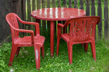 Czerwony plastikowy stary i opuszczony zestaw mebli ogrodowych