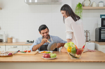 Happy young couple cooking together in the kitchen at home