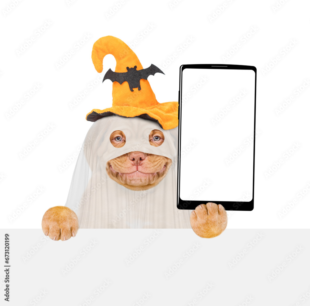Poster smiling mastiff puppy celebrating halloween in ghost costume, showing big smartphone with white blan