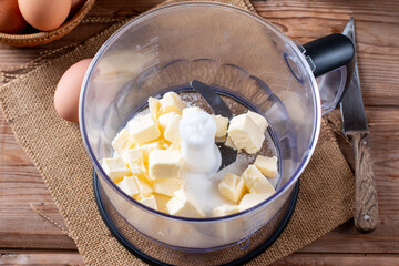 From above blender bowl with butter and sugar on a table
