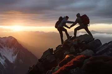 Papier Peint photo Montagnes Two mountaineers offer helping hand on a rock ridge at sunrise above a valle