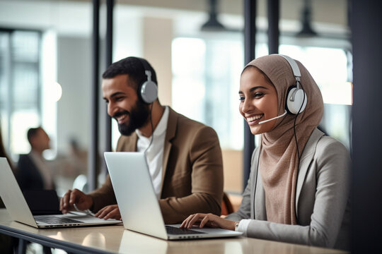 Two Coworkers Collaborating and Celebrating Their Accomplishment in a Modern Office, Muslim Female Trainer Using Laptop to Onboard a Black Male Customer Support Agent and Answering His Question