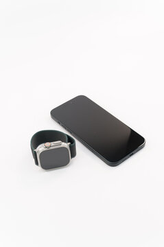 immagine editoriale illustrativa primo piano di Apple Watch Ultra 2 e apple iPhone 15 Plus su superficie bianca