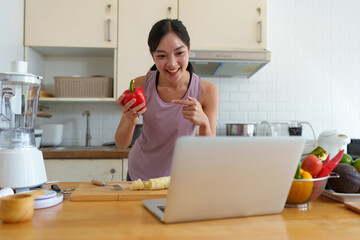 Confident young woman in exercise clothes talking Live broadcast via laptop computer presenting bell peppers that are beneficial to the skin excretory system shape proportions After exercising at home