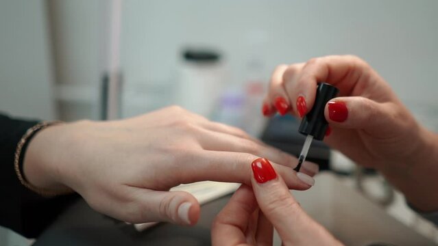 Beauty manicurist doing nails to a female client in a beauty salon, hands close-up