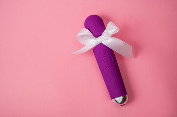 Purple vibrator with a white bow on a pink background. Women's gift. 