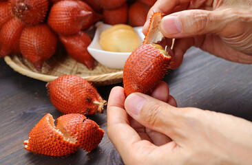Hand Pinching and Pulling the Tip of Snakeskin Fruit to Peel It Off