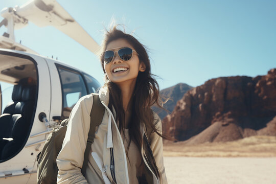 Happy young woman getting off a helicopter to explore a desert