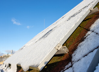 Snowy solar panels on the roof of a house.
