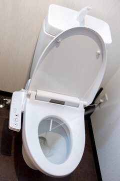 Toilet bowl with electronic control bidet. Water sprays from toilet bowl. 
