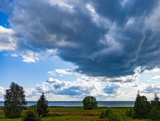 Obraz premium Summer landscape with lake, grass, trees against a blue sky with white clouds