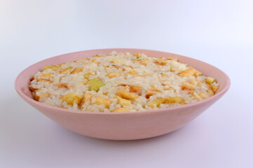 Rice porridge with apples in a pink bowl on a white background.