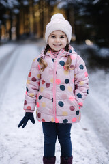 Happy little girl walking in snowy winter forest. Near year mood