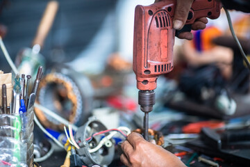 Selective focus to tools and hand of an electric motor repairman. Mechanic is repairing an electric motor. Electric fan motor repair work .