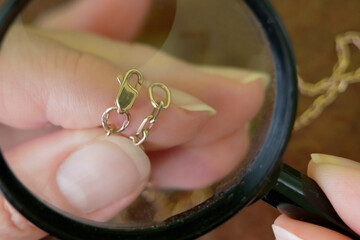 jeweler looking at golden chain through magnifying glass, jewerly inspect and verify, pawnshop