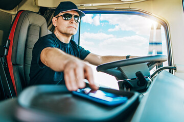 Portrait of handsome middle age man professional truck driver sitting and driving big truck. He is...