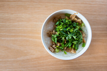 Pork porridge sprinkled with coriander in a paper white bowl