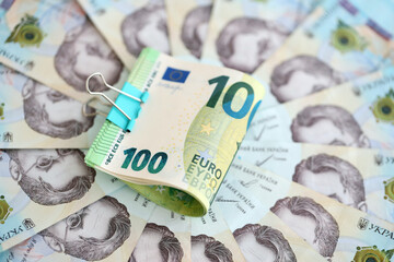 Bunch of hundred euro bills lies on many banknotes of ukrainian hryvnias. Economical default,...