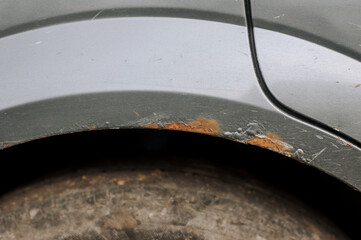 Body near the arch with rust, dirty surface stained with old gray car paint peeling off. Close-up...