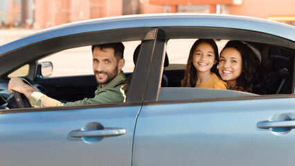 Happy family in car, father driving with daughter and wife
