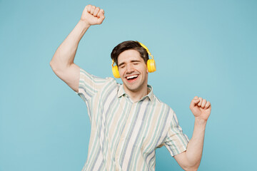 Young happy cheerful man he wear striped shirt casual clothes listen to music in headphones dance...