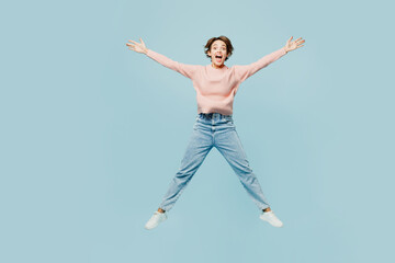 Obraz premium Full body young excited overjoyed happy woman wear beige knitted sweater casual clothes jump high with outstretched hands legs isolated on plain pastel light blue cyan background. Lifestyle concept.