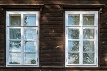 Two rectangular windows with a visor and white frames on a wooden wall in a log house. From the Windows of the world series.