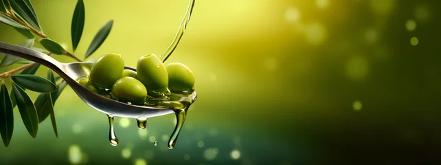 Fototapeten Branch of olive fruit and olives with drops of oil in spoon on blurred green background. © petrrgoskov