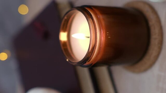 Autumn home disign: burning candle, with lights and glasses on table in cozy living room.