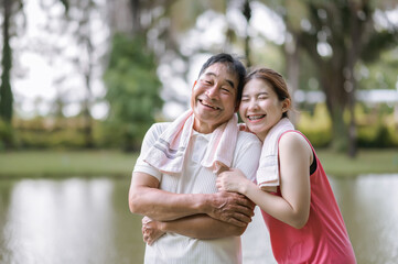 Asian Elderly father and daughter in sportswear show love and care for each other in a green park. Healthcare and family bonding.