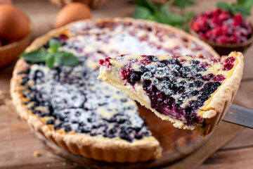 Closeup homemade berry pie with raspberry and blueberry on a wooden table.