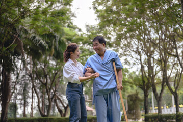 Daughter takes care of father and helps Support, Encourage him during his illness at hospital garden. The happiness of old adult patients while rehabilitation or physical therapy of retired patients.