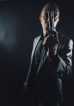 Spy in elegant suit with pistol gun in dark