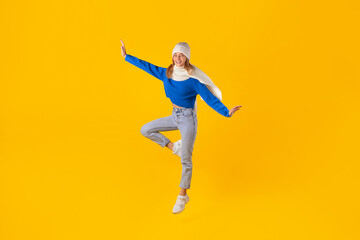 Energetic woman jumping and celebrates winter sales on yellow background