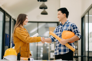 Obraz premium Engineers or architecture shaking hands at construction site for architectural project, holding safety helmet on their hands.