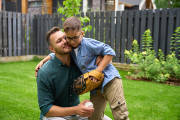 Father and son play baseball on the lawn of house