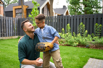 Father and son play baseball on the lawn of house